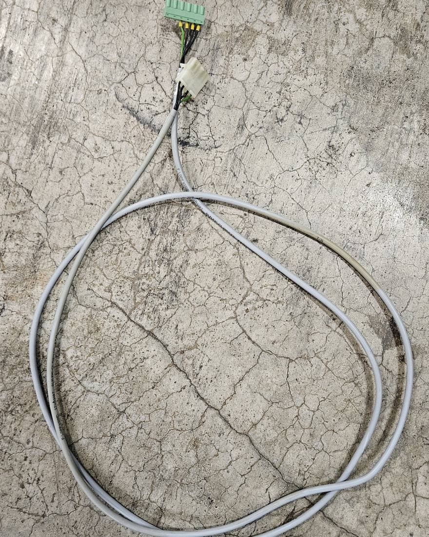 Undocumented sample cable coiled on a mill shop floor, terminated in a pluggable terminal block